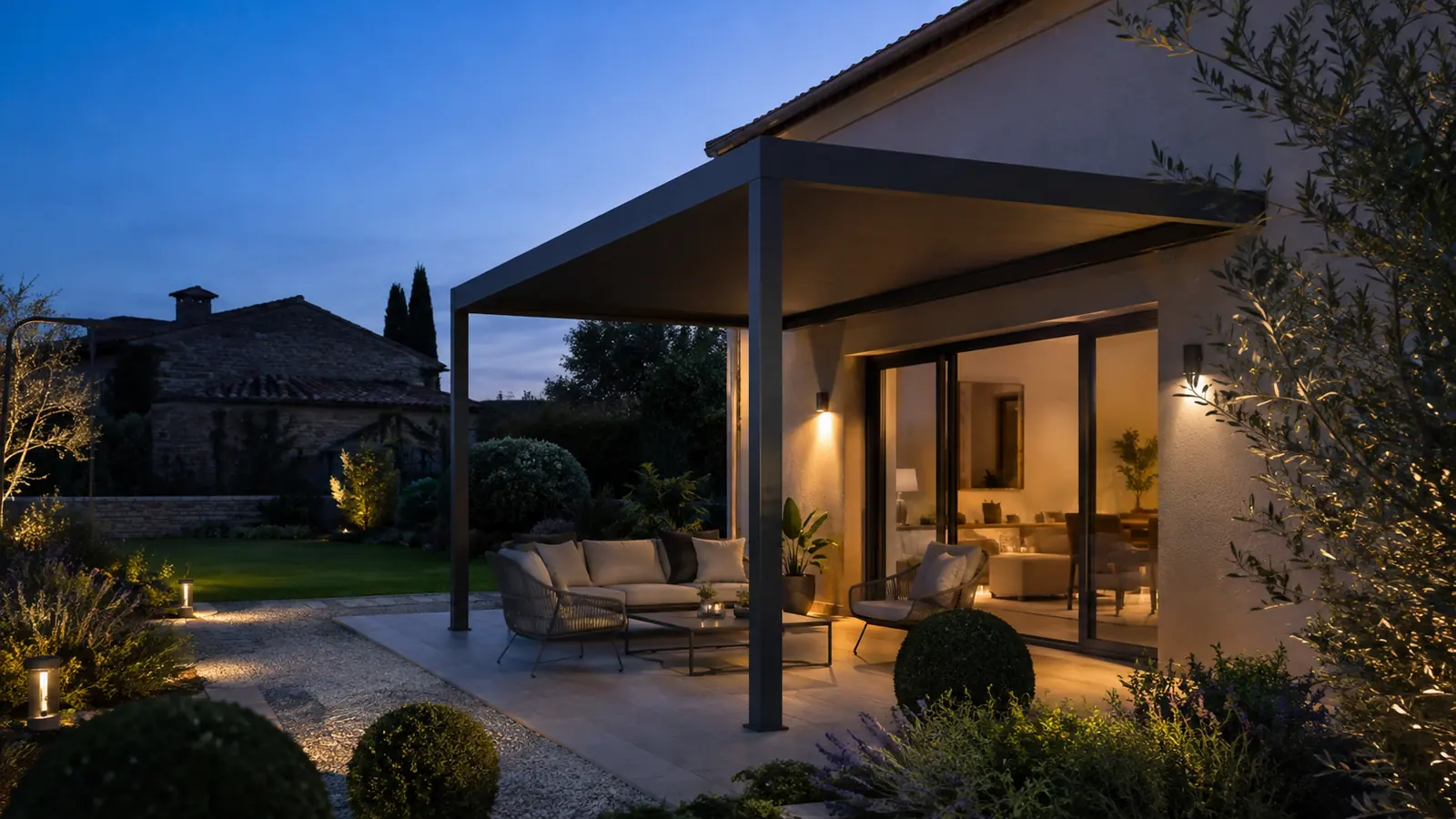 Terrasse au crépuscule sous une pergola anthracite avec salon extérieur éclairé
