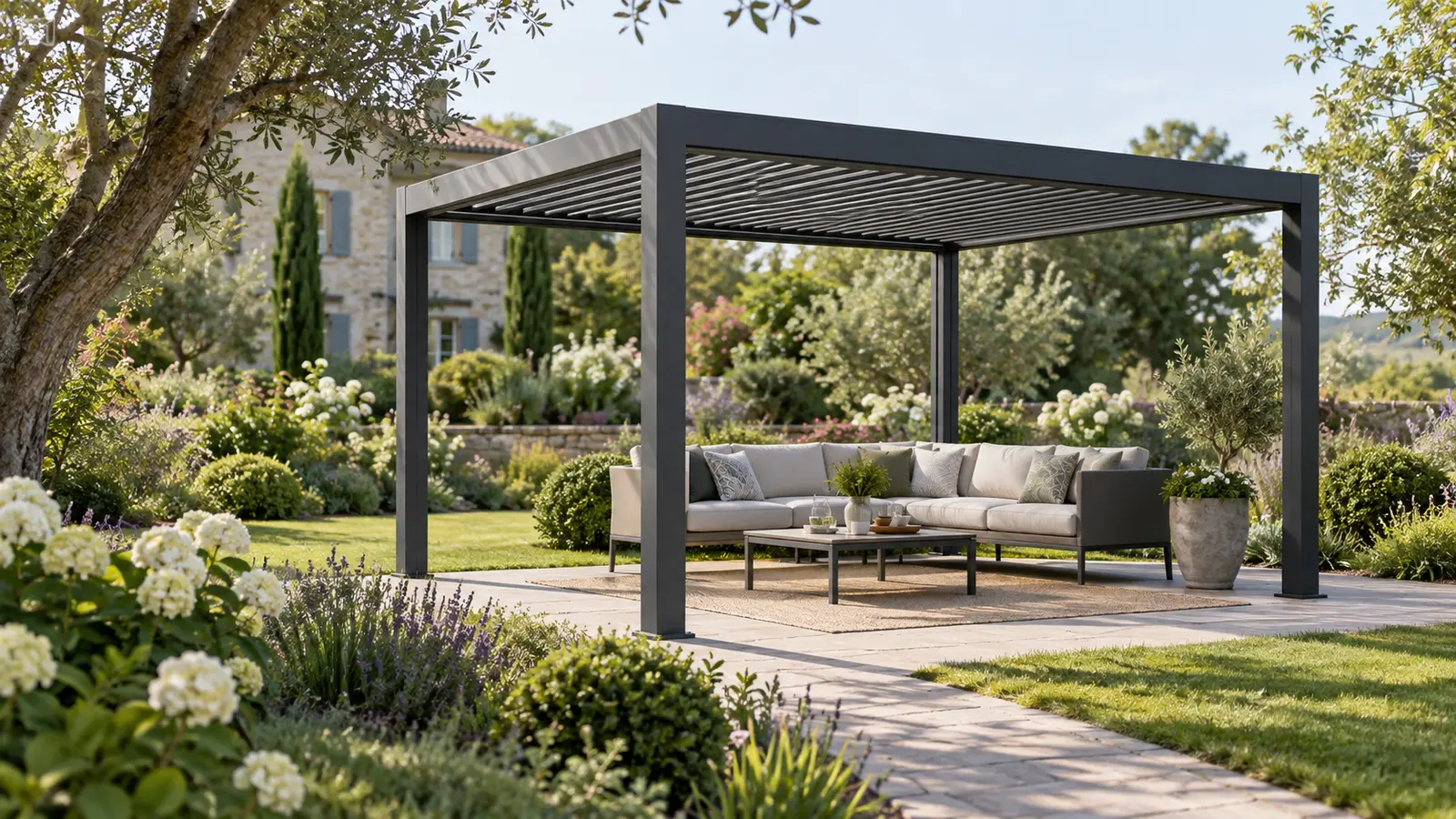 Pergola autoportée anthracite avec salon extérieur au milieu d’un jardin planté