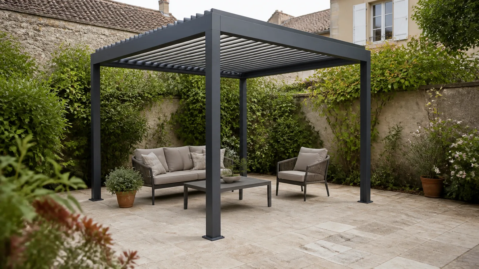 Pergola autoportée anthracite 3x3 avec petit canapé, fauteuil et table basse dans une cour végétalisée