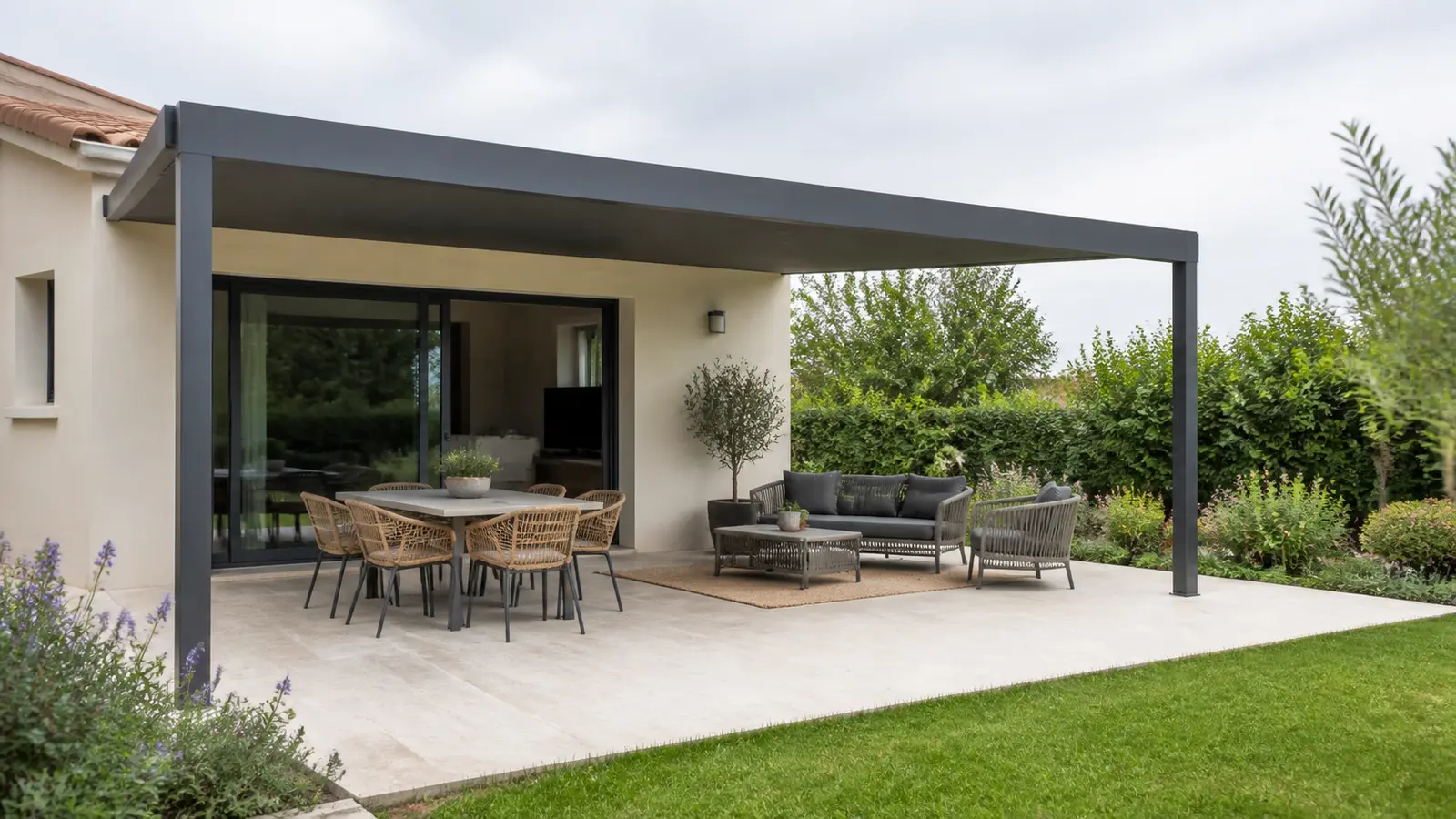 Terrasse sous pergola anthracite avec table près de la baie et salon extérieur côté jardin