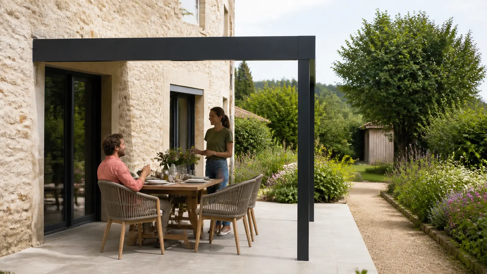 Table de terrasse et passage vers le jardin sous un cadre de pergola adossée anthracite