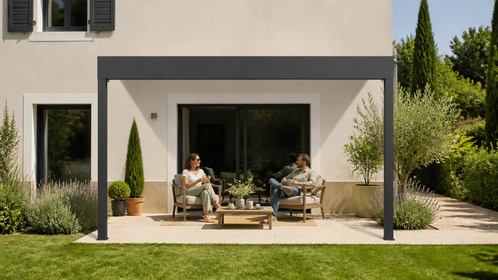 Deux fauteuils sur une terrasse de plain-pied bordée d’un jardin planté