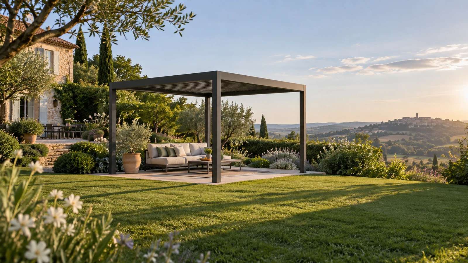 Pergola autoportée anthracite installée face à un jardin ouvert avec canapé extérieur et lumière de fin de journée
