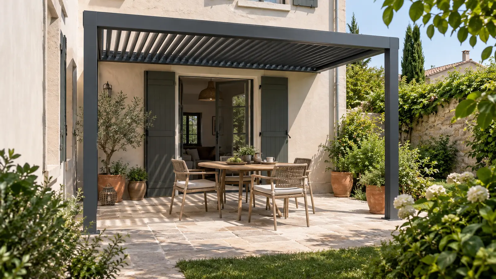 Petite terrasse avec table ronde sous une pergola anthracite adossée à une façade claire