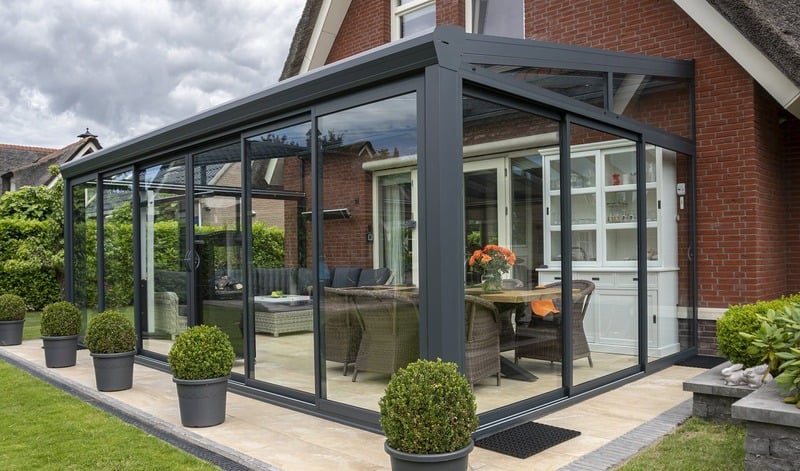 Veranda moderna con grandes ventanales y mobiliario contemporáneo